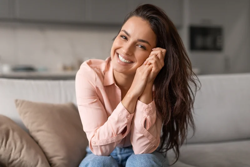 A smiling woman seated on a sofa